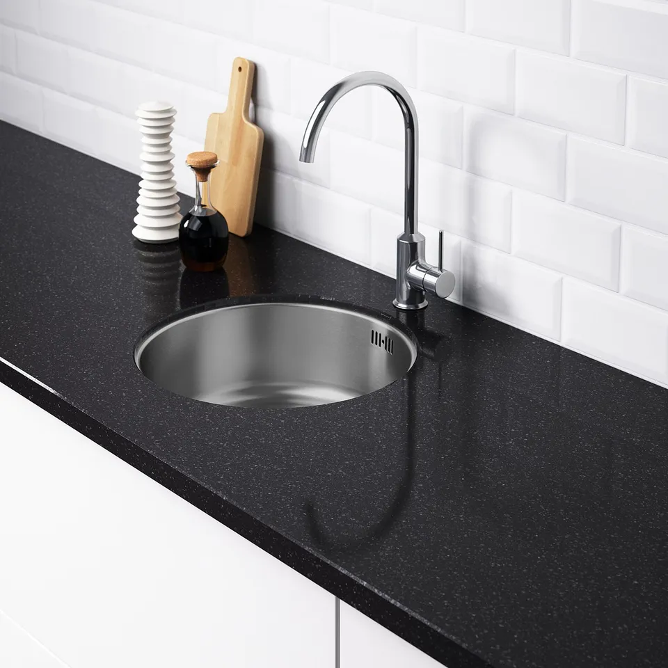 Modern kitchen sink with chrome tap and black countertop. Stainless steel sink, no pre-drilled holes. White tiled backsplash.