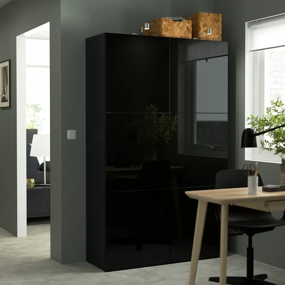 Black BESTÅ unit with glass doors and basket on top, in modern minimalist room.