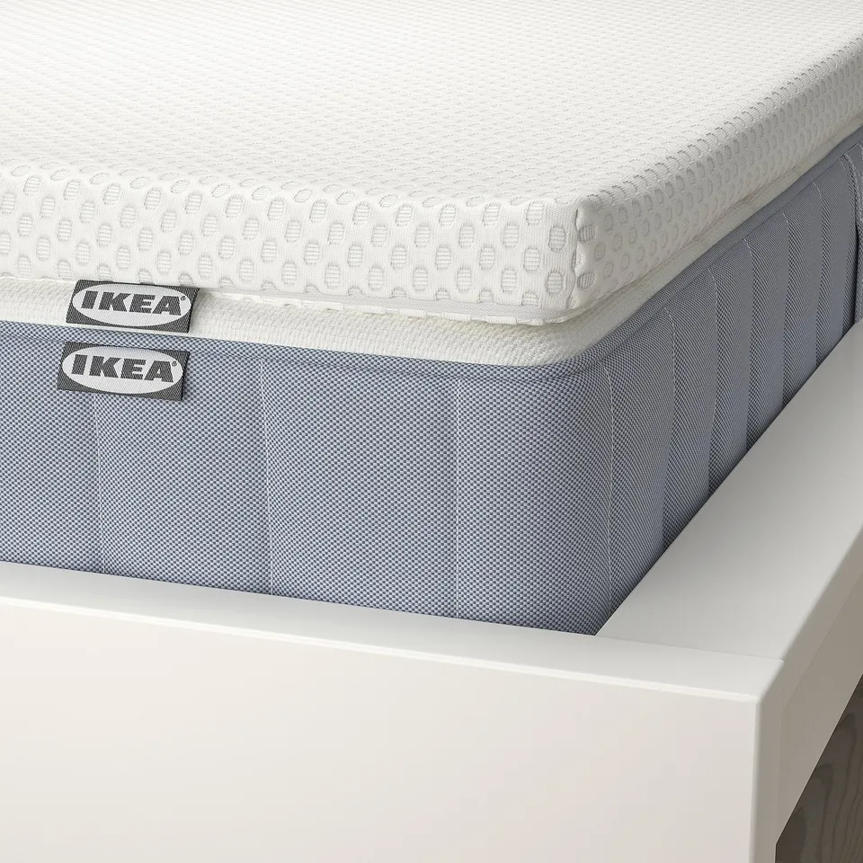 IKEA mattress stack: white topper, blue base, brands visible.