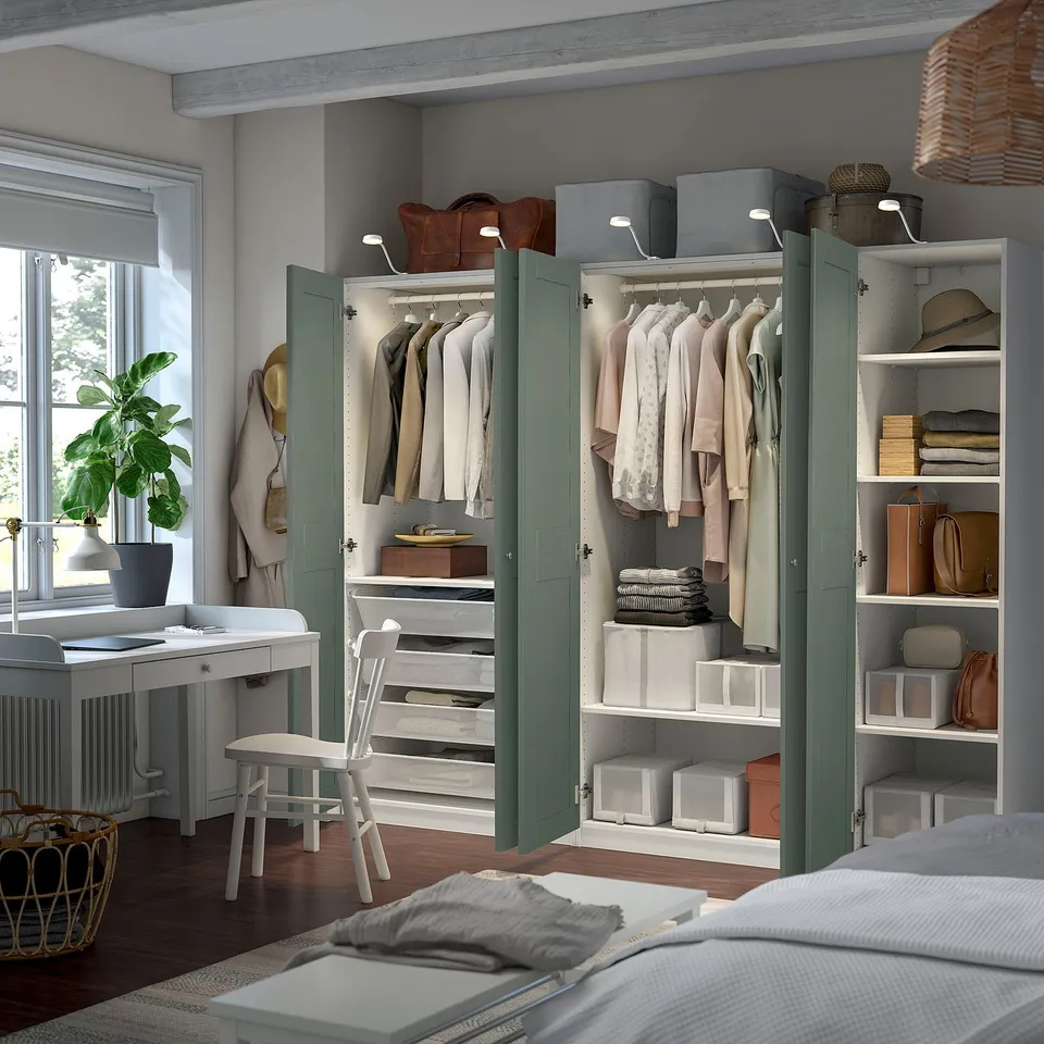 A modern bedroom an open wardrobe system with foldable clothing, shelves, and a desk. Wardrobe lights illuminate neatly arranged items.