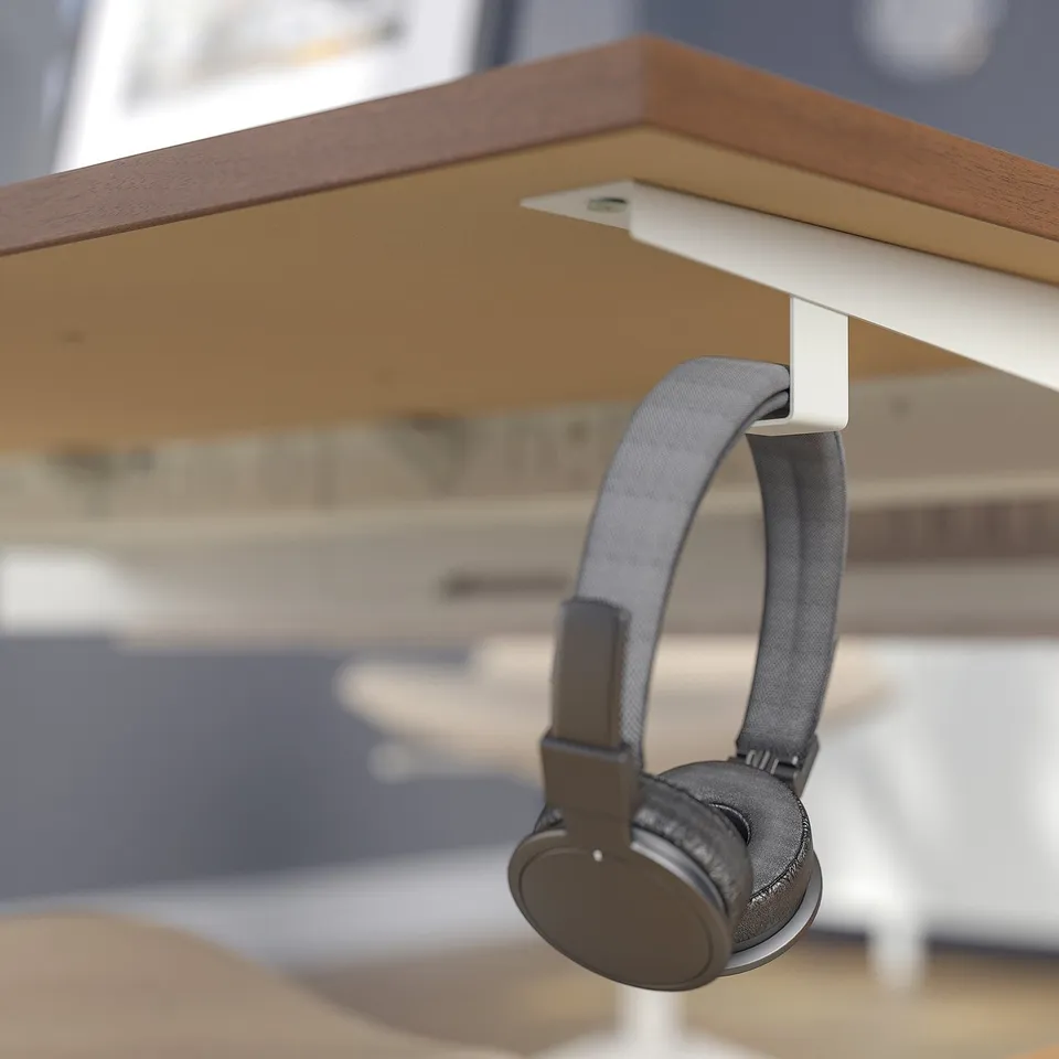 Headphones hang neatly from a hook under a wooden desk, keeping the workspace organised.