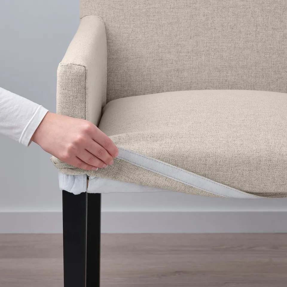 Person showing STRANDTORP chairs removable, washable cover, highlighting easy cleaning and comfort.