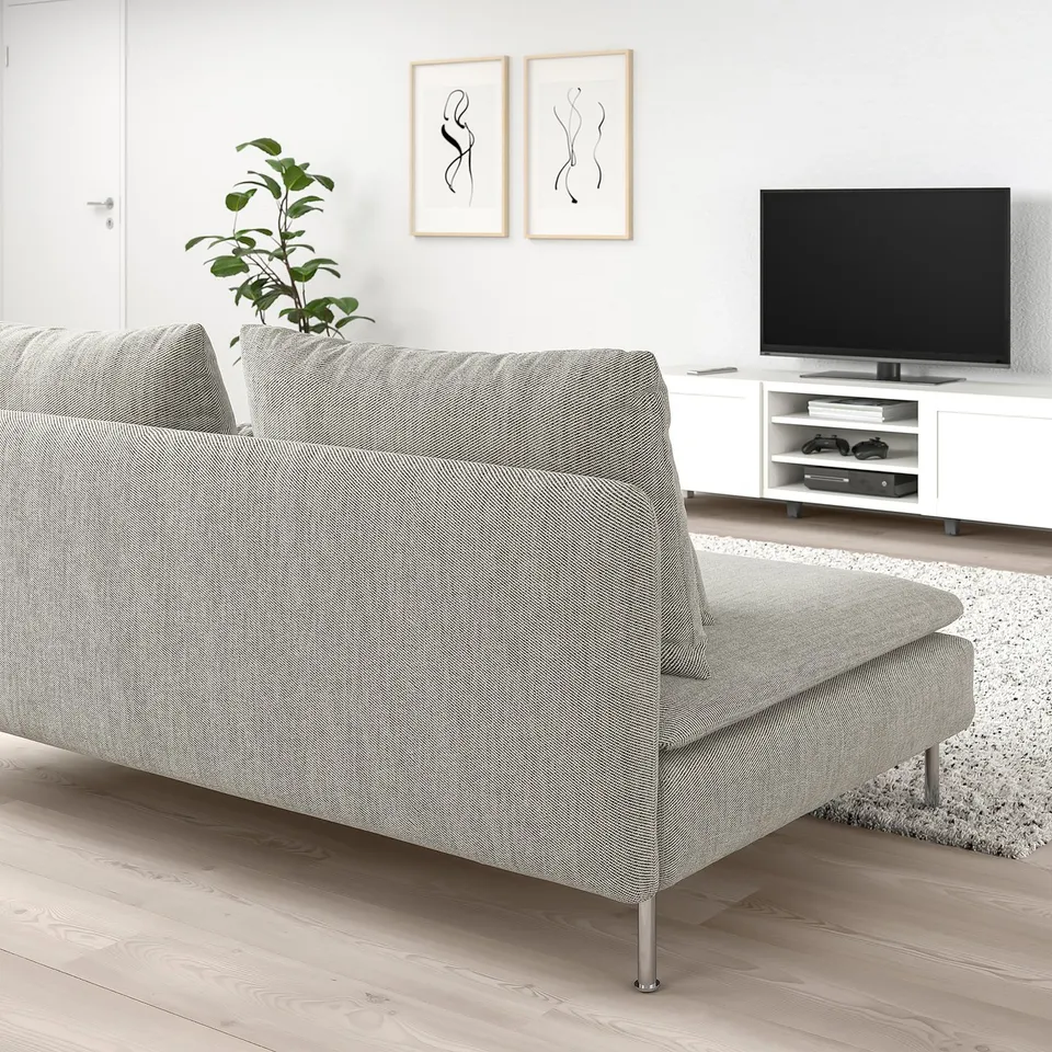 SÖDERHAMN sofa in light grey with loose cushions. Beside it, a white tv unit with gaming consoles. Minimalist room decor includes plant, art, and rug.