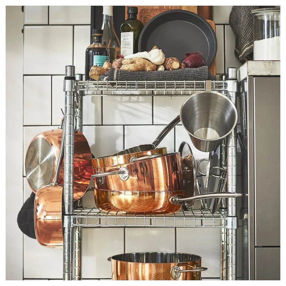 Metal kitchen shelf holding copper pots, pans, and other items.