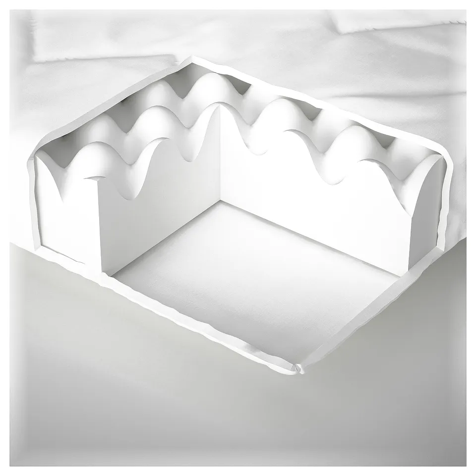 A white cushion with textured top, filled with foam, placed on a white surface.
