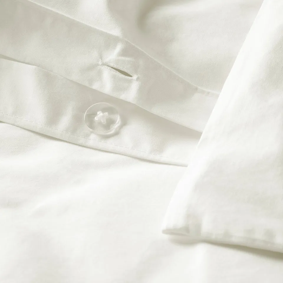 Close-up of crisp white bedding with a single button and neat folds, showcasing quality craftsmanship.
