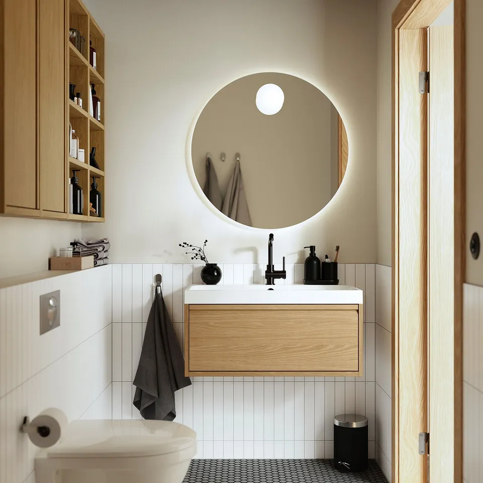 Elegant FAXÄLVEN mirror highlights bathroom. Round lighted mirror with wooden cabinet. Perfectly sized, providing spacious feel.