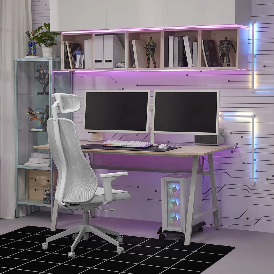 Home office with purple lights, dual monitors, white chair, action figure display.