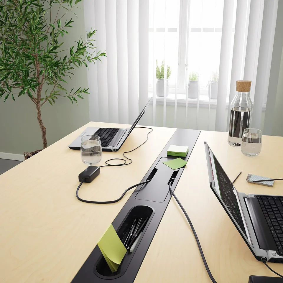 Modern conference table with built-in power outlets and cable management, perfect for meetings or coworking.