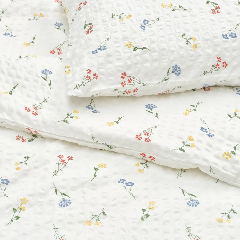 Elegant white duvet cover with colourful floral prints, showcasing high-quality fabric and intricate seersucker texture.