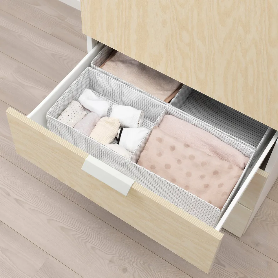 Open wooden drawer with folded blankets and pillows, part of platsa storage system.