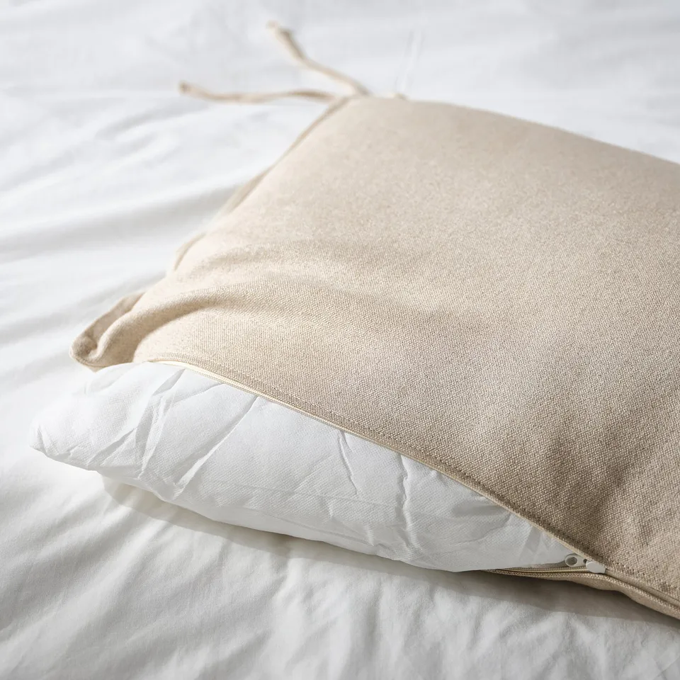 Unzipped pillowcase revealing rhythmic stitching and soft fabric, showcasing adjustable bedding detail.