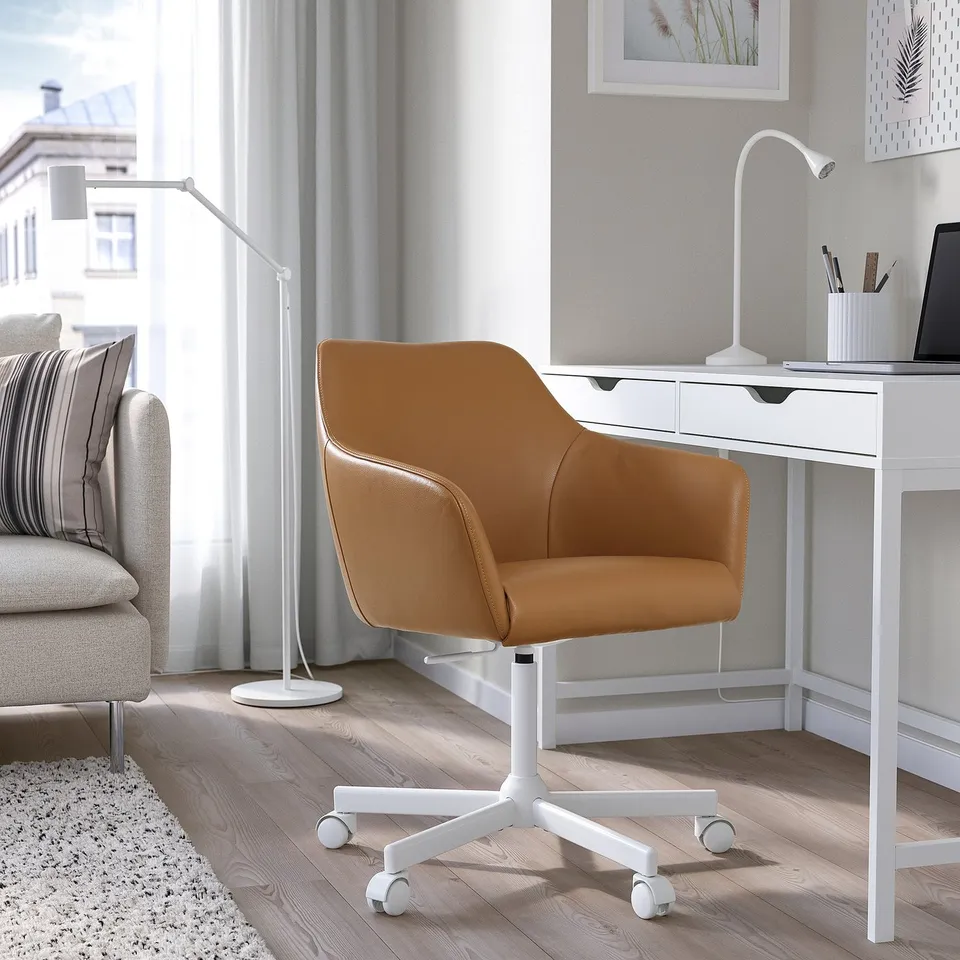 Brown leather TOSSBERG swivel chair by desk in bright room, medium size, stylish.