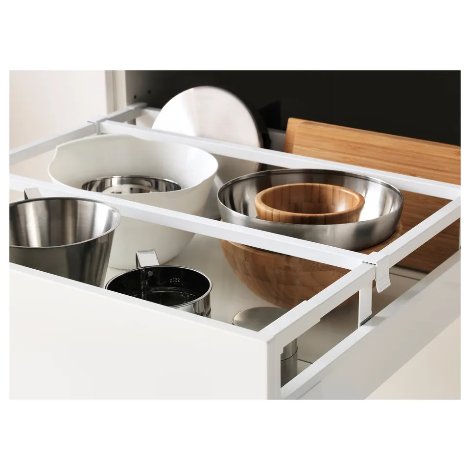Open kitchen drawer showing stainless steel pots, wooden bowls, and adjustable compartments.