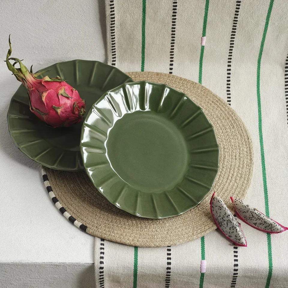 Green glazed stoneware side plate, smaller than a woven mat, with scalloped edge.