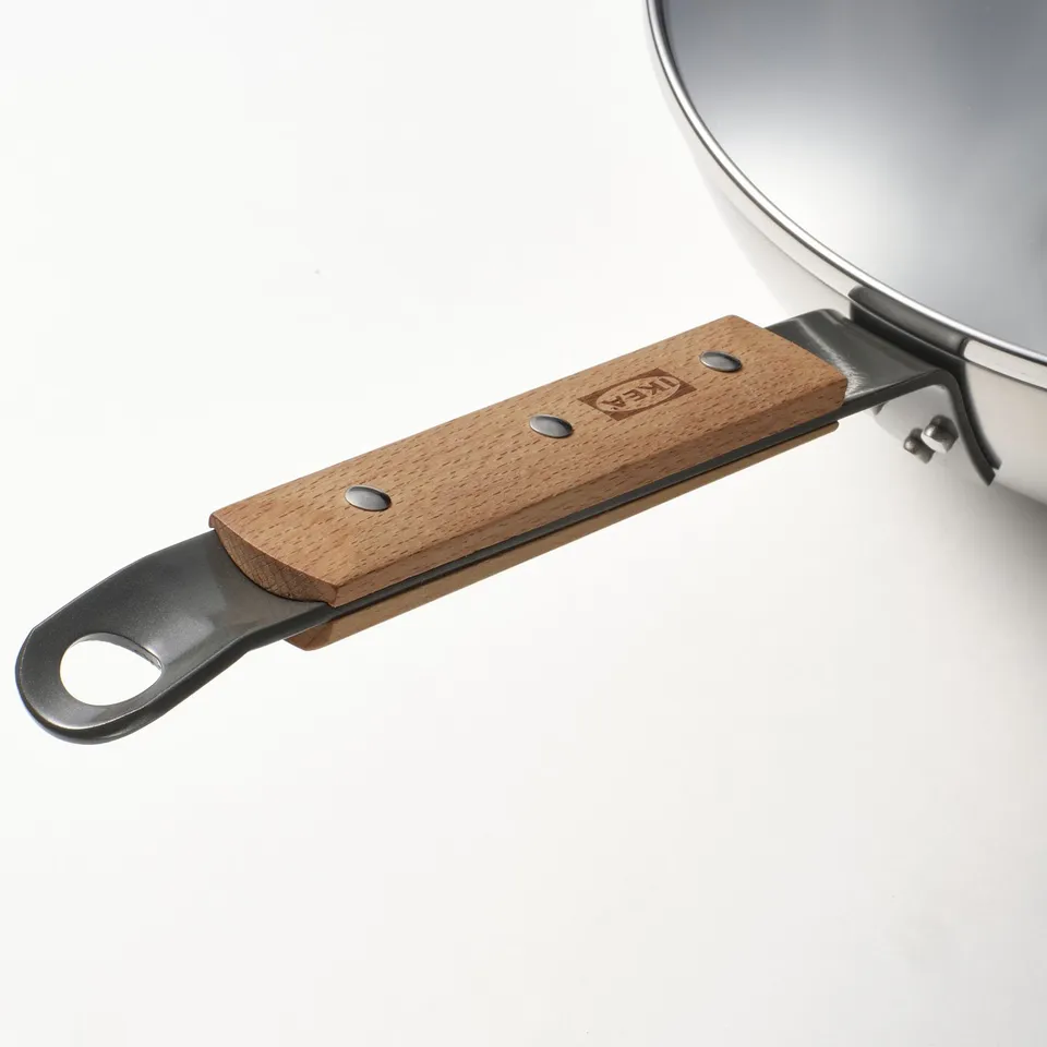 Close-up of a high-quality wok handle with a wooden grip and ikea branding.