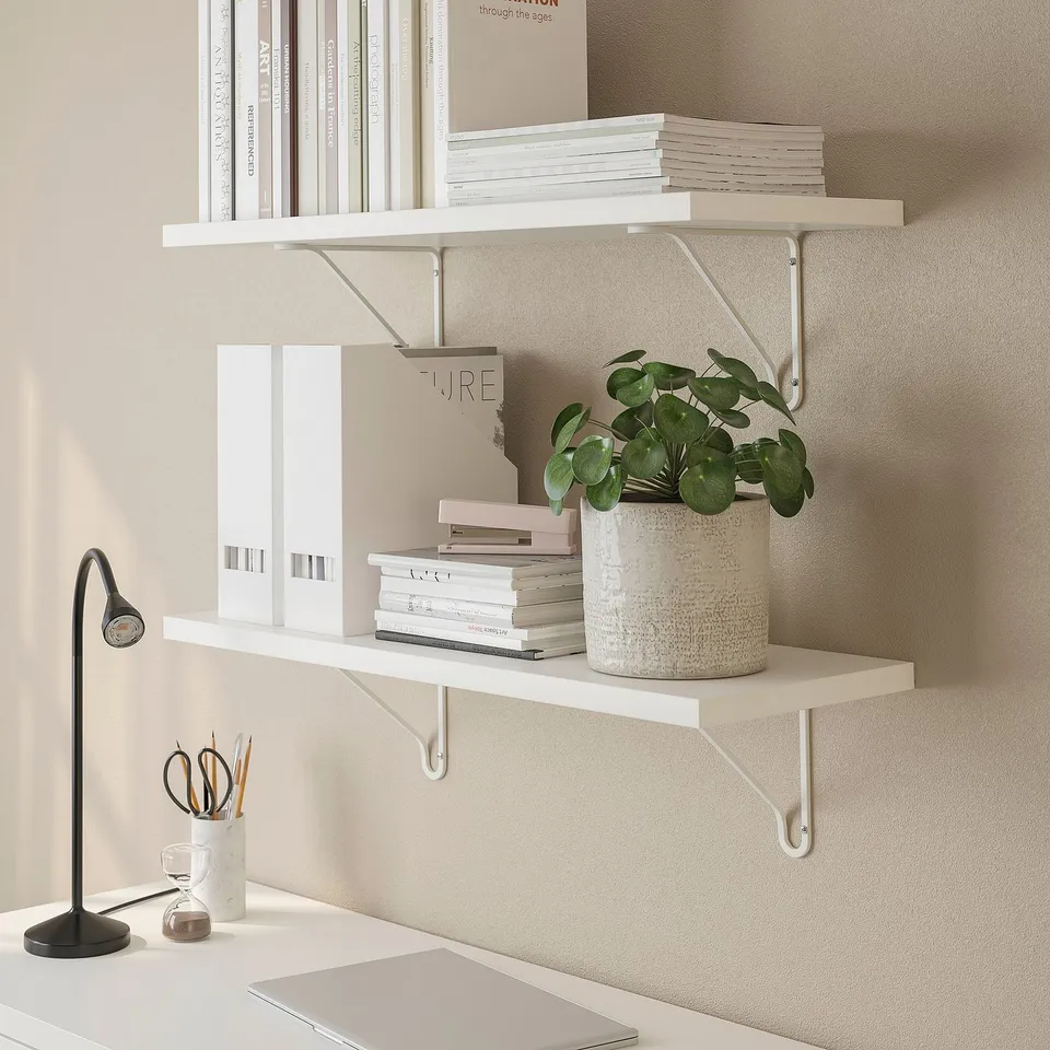 Neutral-colored shelves holding books and a plant, mounted on a wall, providing storage and decoration.