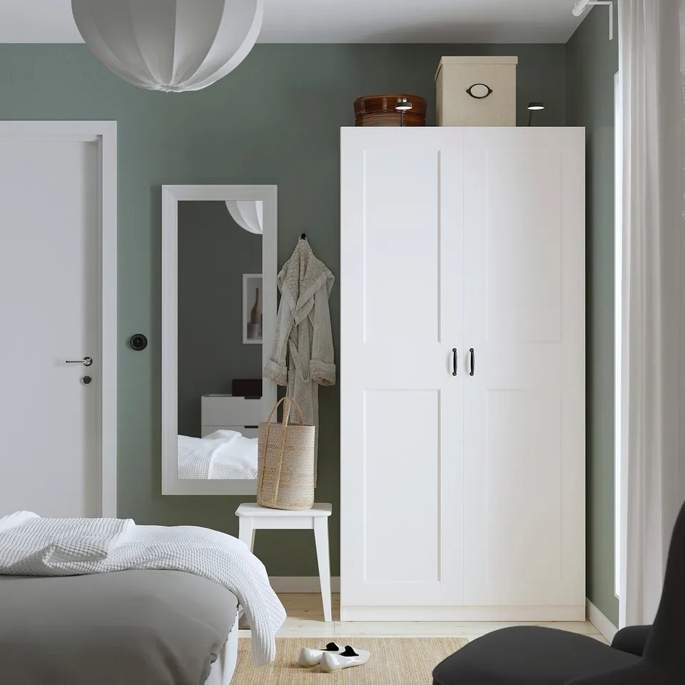 Modern bedroom with white PAX wardrobe and mirror reflecting the room.