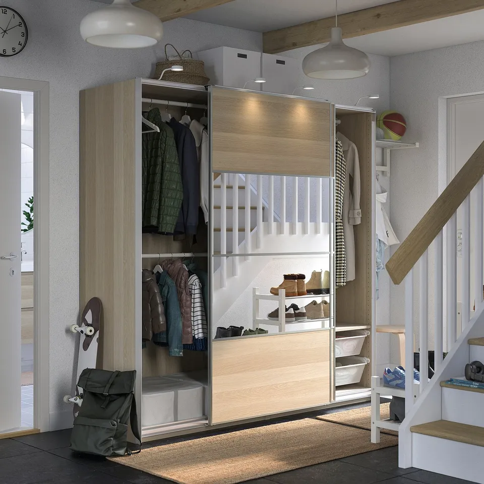 Organised closet with sliding doors, winding staircase, backpack, jackets, hats.