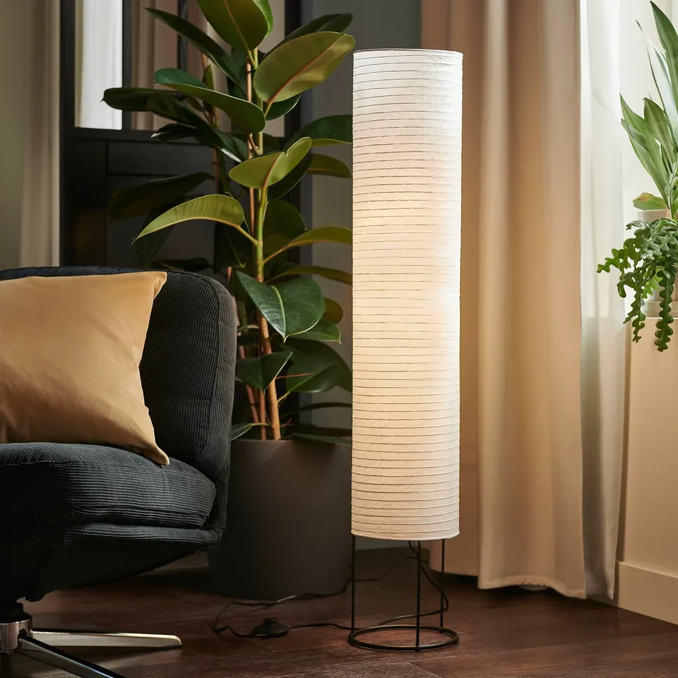 Modern living room with STRANDAD floor lamp beside armchair and plant.