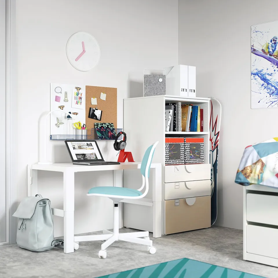 Kids study area with SMÅSTAD desk, blue chair, bookcase, corkboard, clock, and painting.