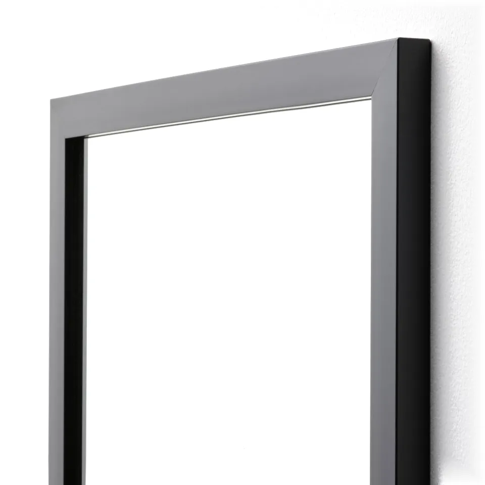 Leaked modern mirror with sleek matte black frame, mounted on wall, reflecting clean, bright surface.