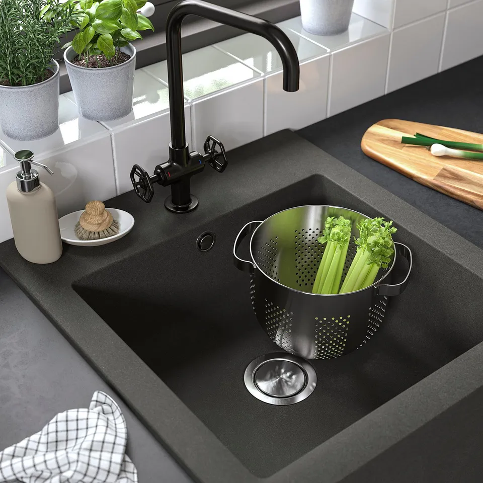 Black farmhouse-style sink with vegetables in a strainer.