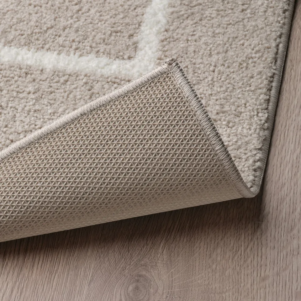Close-up of soft, beige rug with textured, non-slip backing for stability and safety.