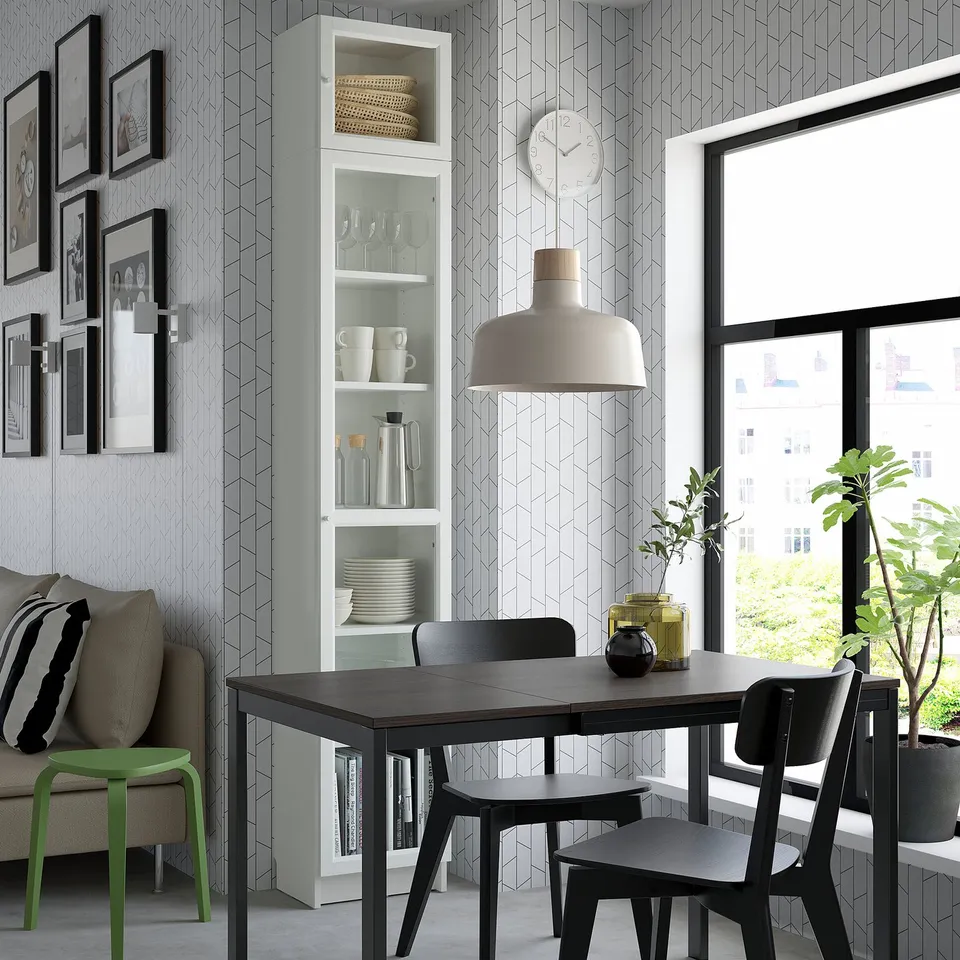 Modern dining area with black table, chairs, green stool, BILLY bookcase, clock, lamp, plants, photos, and city view.