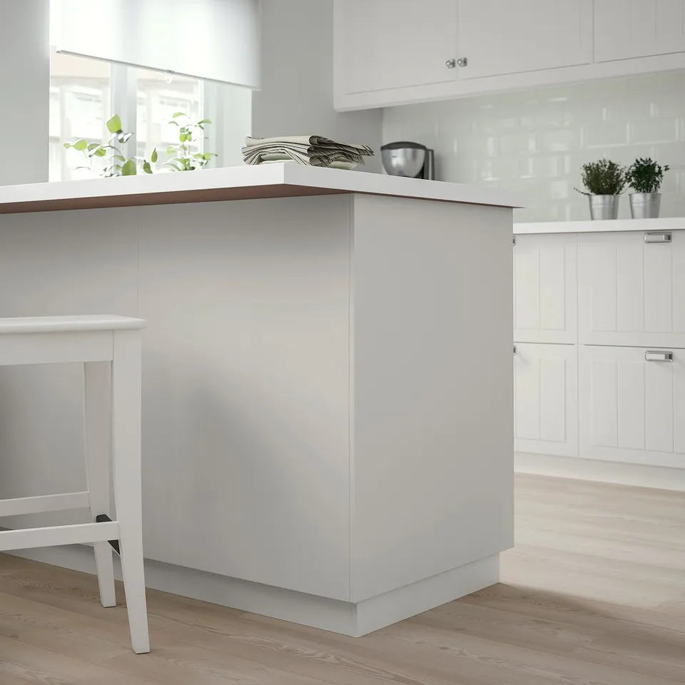 Modern white kitchen with light wood floors, central island, plant, minimalist design.