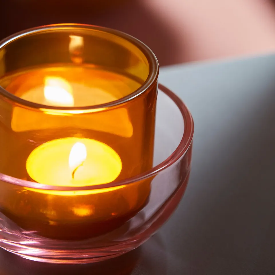 Golden glass tealight holder emits soft light, showcasing elegant design.