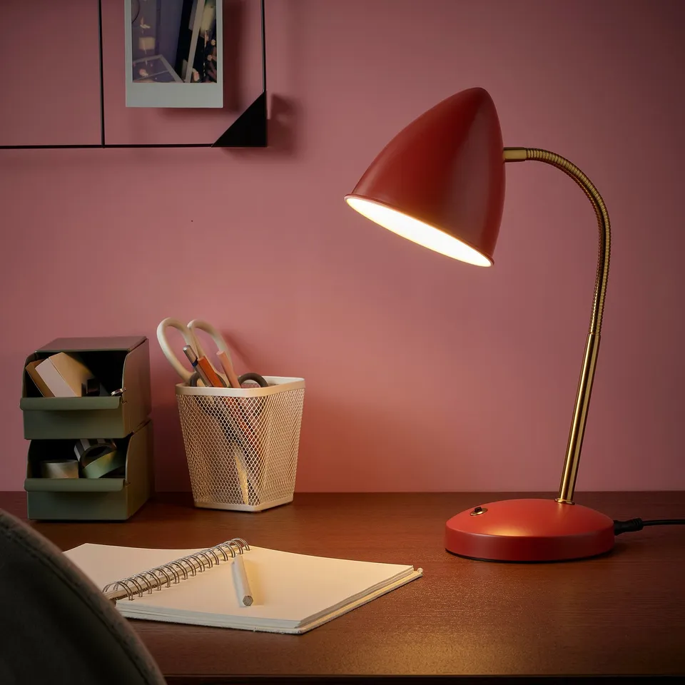 Red ISNÅLEN lamp with flexible gold neck, lighting notebook.