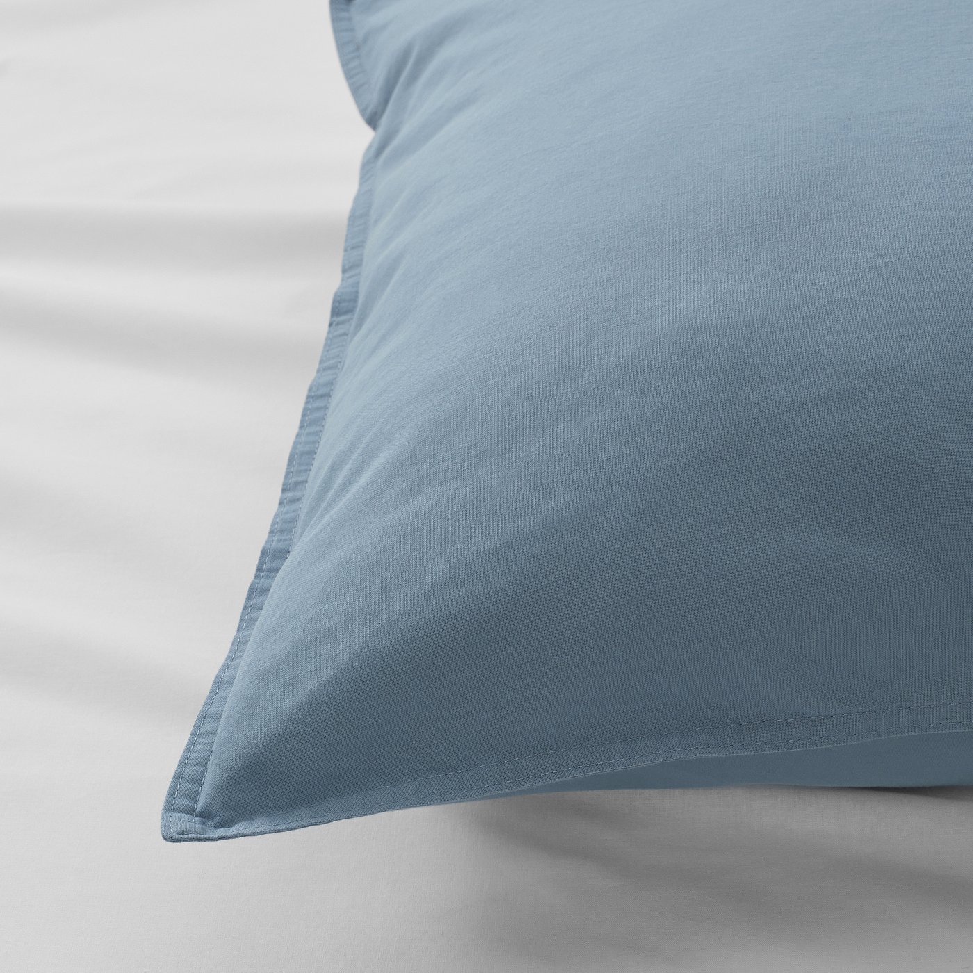 Light blue pillowcase with neat stitching, smooth texture, on a white surface.