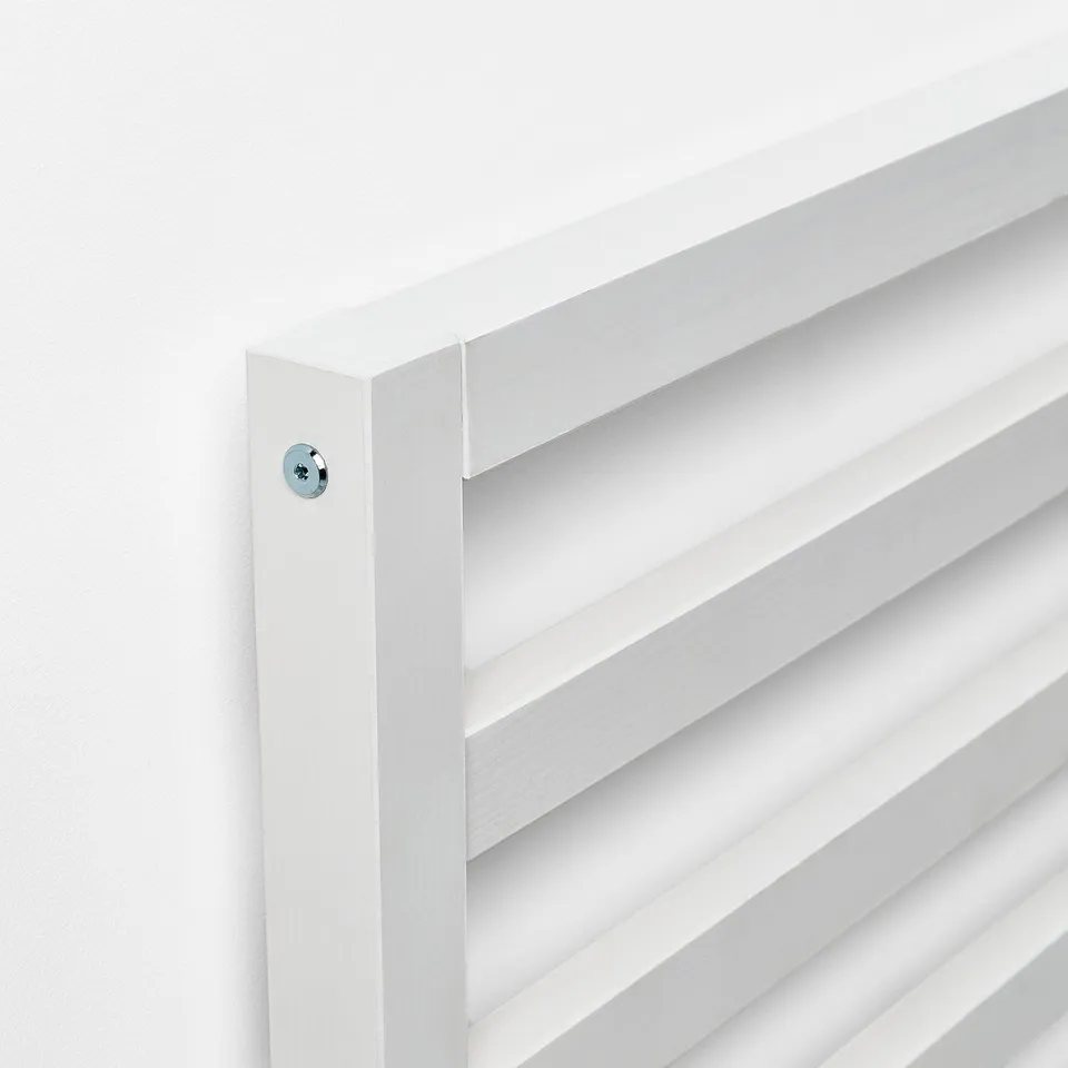 A close-up of a white TARVA bed frame featuring visible metal screws and slatted design, highlighting its robust and simple aesthetic.