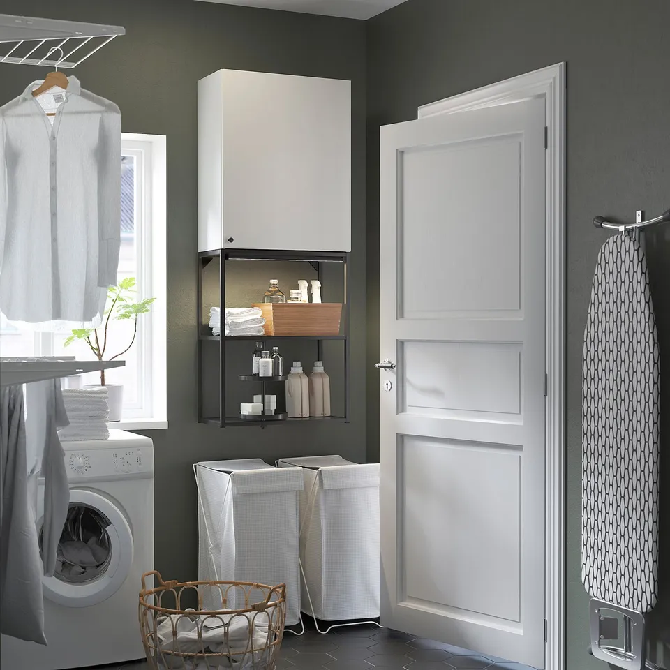 Laundry room with ENHET storage, clothes, washer, and towel basket near door.