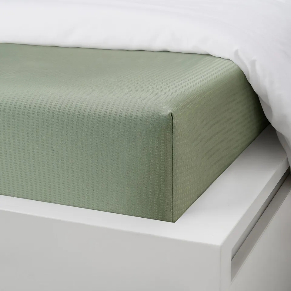 Green fitted bed sheet, elastic corners, fits mattresses up to 26 cm thick.