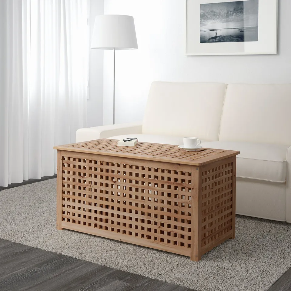 Wooden side table with grid-pattern lid sits by white couch, serving as both storage and display area.