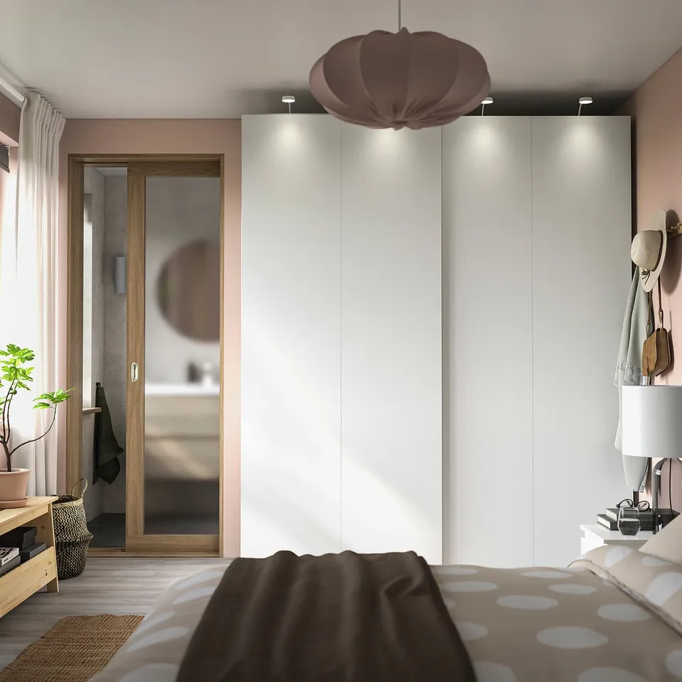 Modern bedroom with sliding wardrobe, polka dot bedding, pendant lamp, mirror, side table, hanging plants, bench.