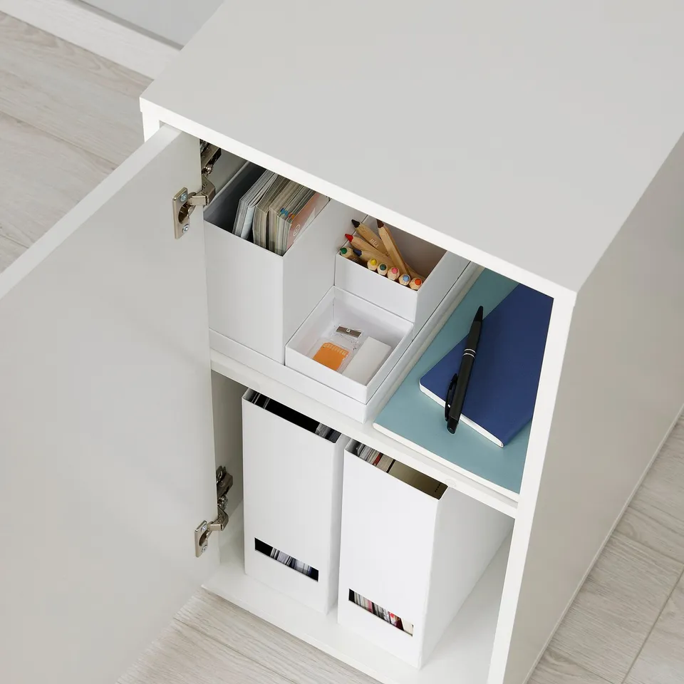 White cabinet with shelves storing notebooks, pens, and stationery, ideal for organising desk accessories.
