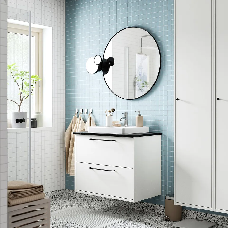 Stylish bathroom with HAVBÄCK vanity, round mirror, and blue tiles. Modern sink with chrome tap and minimalist decor.