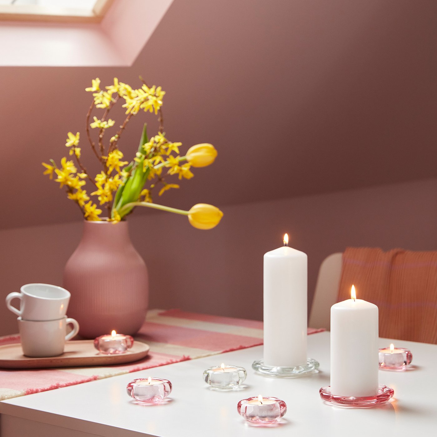 Vase with pink flowers & candles in floral holders.