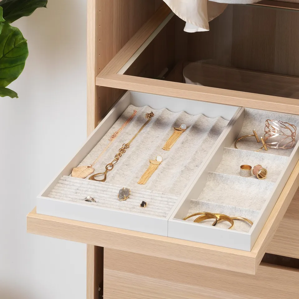 Pull-out jewellery tray with compartments for necklaces, rings, and earrings. Soft felt lining protects accessories.