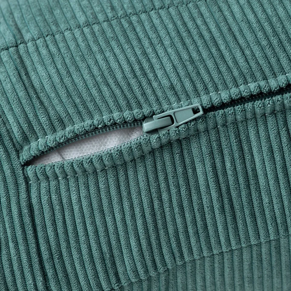 Close-up of soft, teal-green corduroy fabric with visible zip, showcasing texture and detail.
