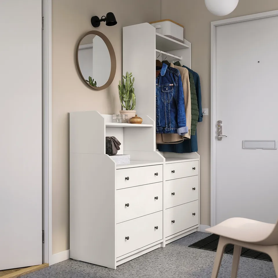 Modern white HAUGA entryway storage set includes wardrobe with hanging space, shelves, and drawers. Topped with a round mirror and decor.