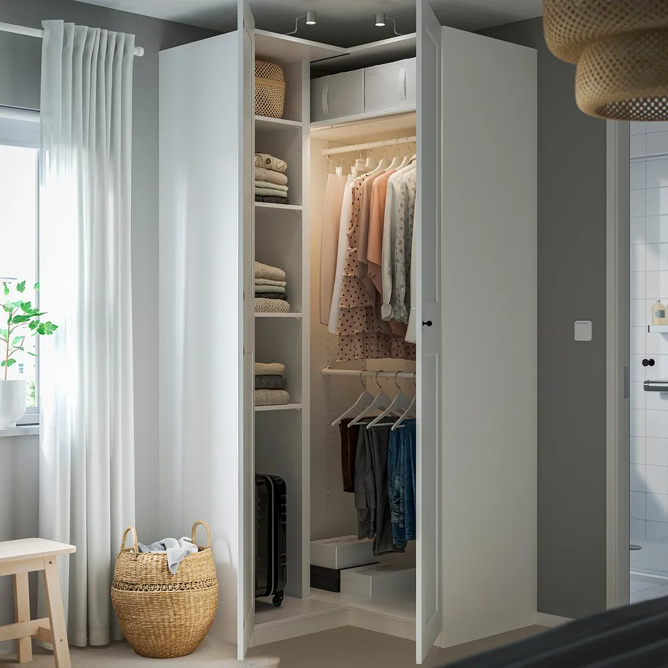 Open wardrobe with clothes, folded towels, and shelves. Includes hanging rail and storage baskets. Interior lit with ceiling lights.