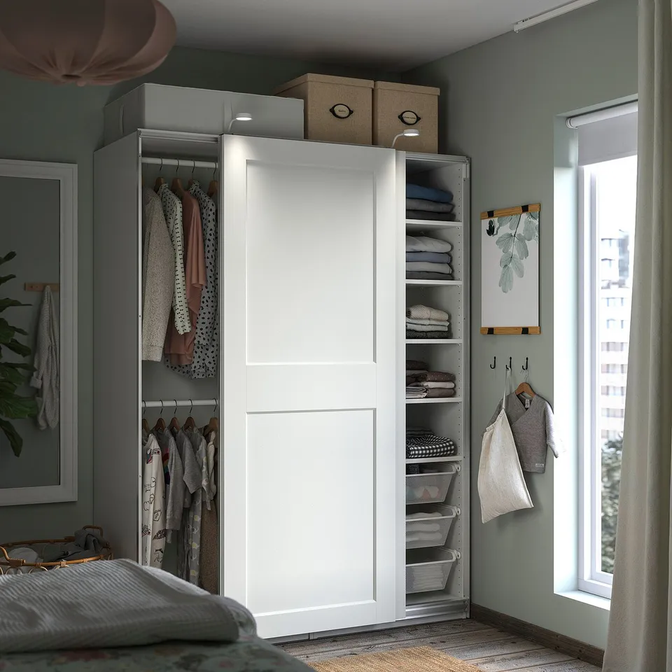 Modern white wardrobe with shelves and hangers. Sliding doors, cloth baskets, and organised clothes. Clutter-free bedroom setup.