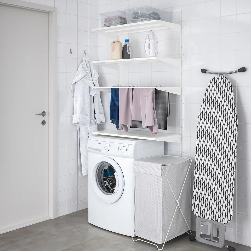 Organised white laundry area with BOAXEL storage, washing machine, dryer, and ironing board.