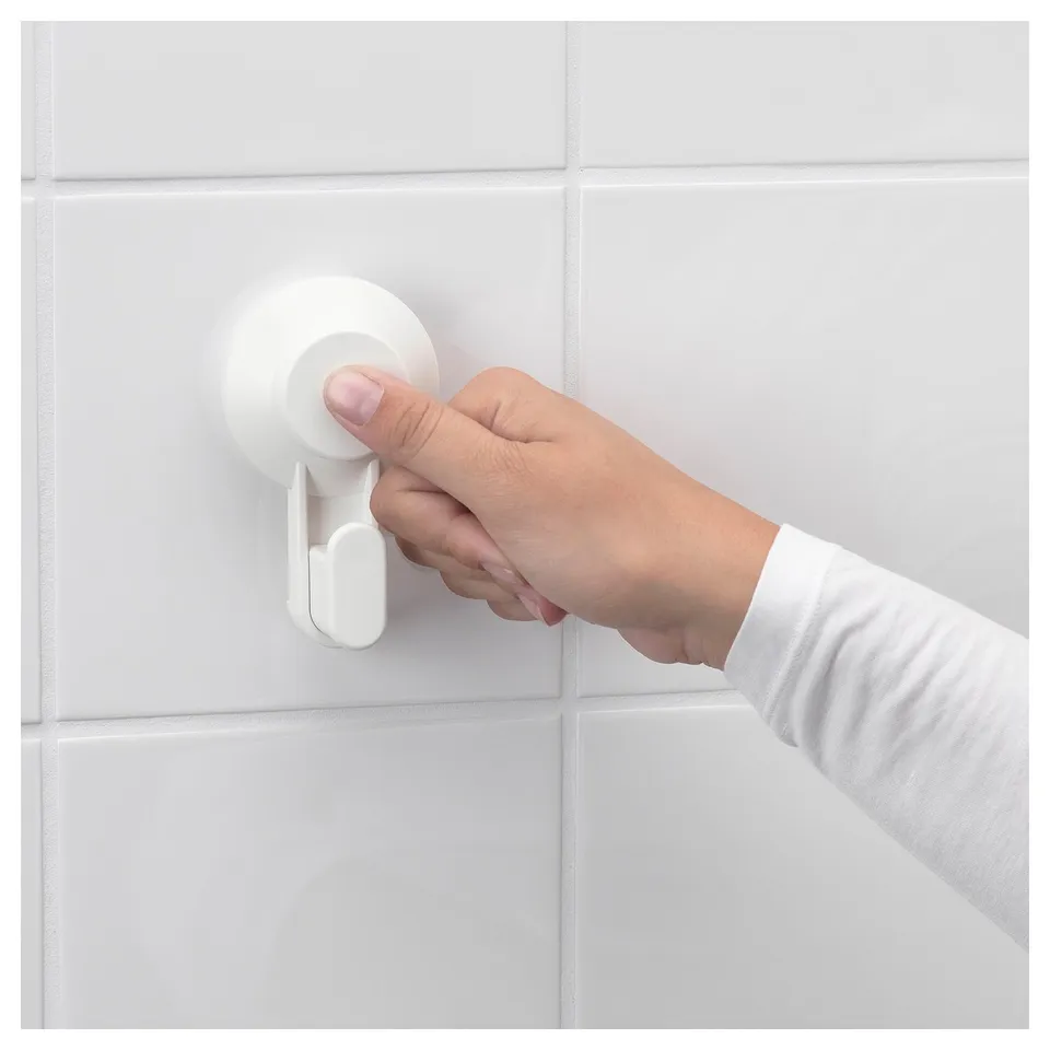 Hand pressing white TISKEN suction cup hook on tiled wall.