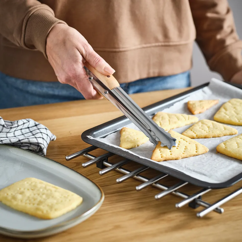 Person uses cooking tweezers to handle baked goods on a tray.