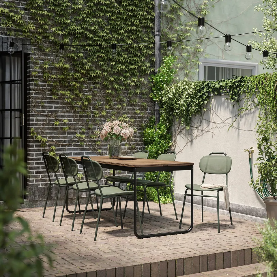 Outdoor patio set with wooden table and green chairs, perfect for dining.